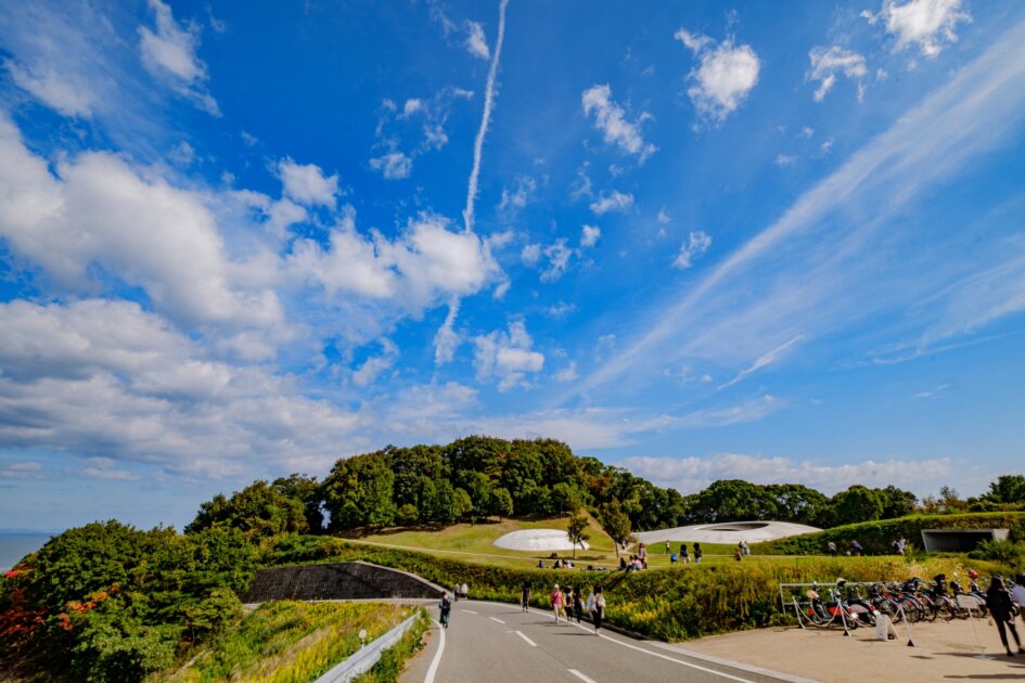 Teshima Art Museum from hilltop showing the white shell structure amid green landscape and blue sky