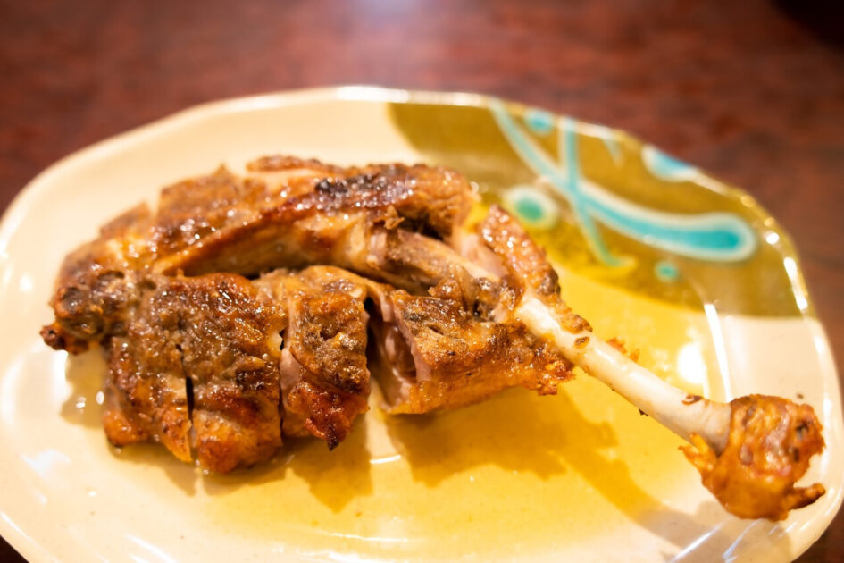 Honetsuki-dori bone-in chicken with crispy skin served on a plate with cabbage